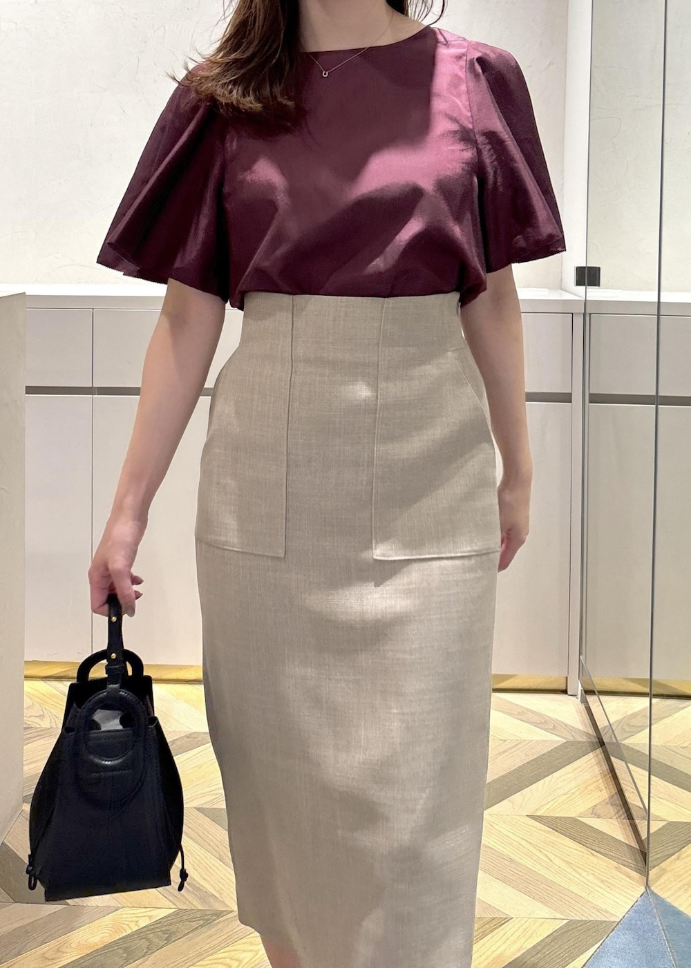 ブラック系のショルダーバッグ、ブラック系のパンプス、ベージュ系のスカートを着用したレディースの夏コーディネートの6枚目の写真