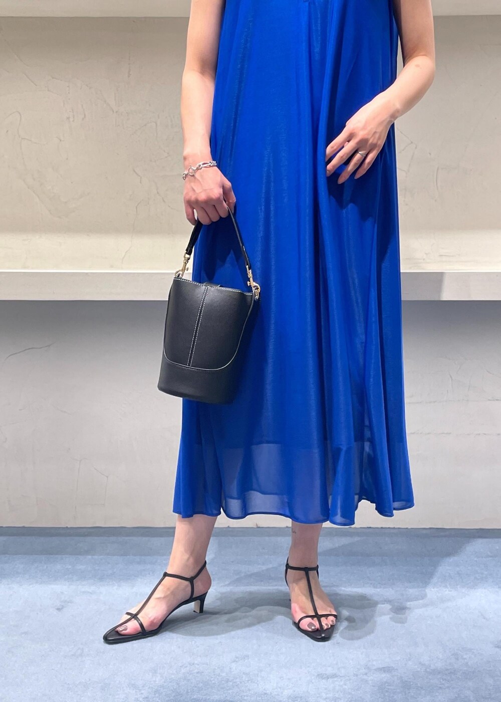 ブラック系のショルダーバッグ、ブルー系のワンピース、ブラック系のサンダルを着用したレディースの夏コーディネートの6枚目の写真