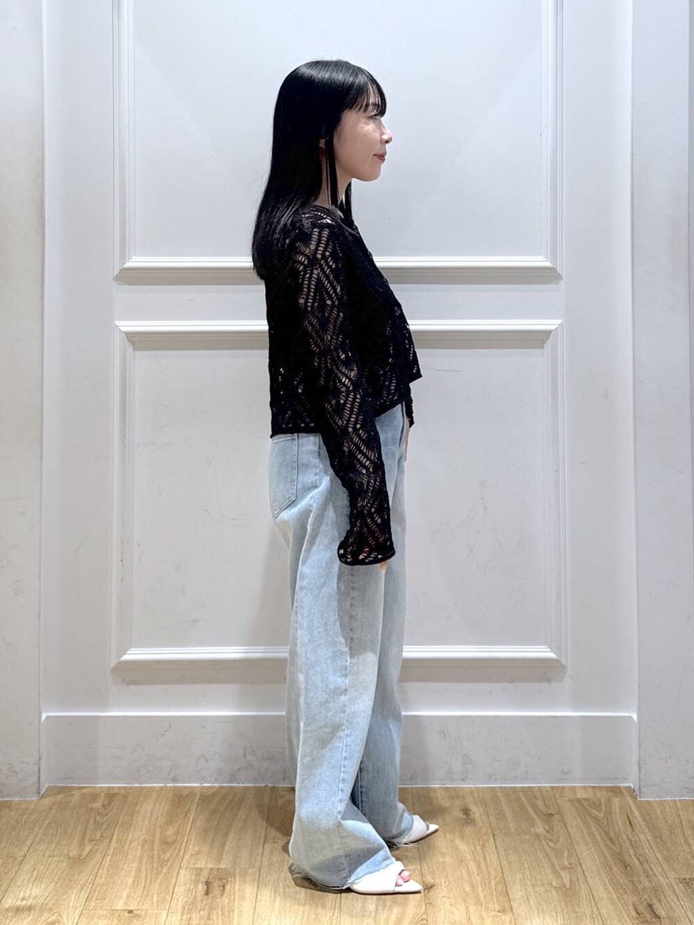 ブルー系のデニムパンツ、ブラック系のカーディガン/ボレロ、ホワイト系のサンダルを着用したレディースの春コーディネートの3枚目の写真