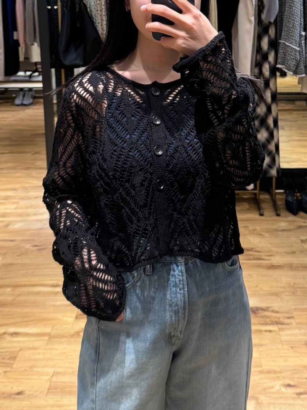 ブルー系のデニムパンツ、ブラック系のカーディガン/ボレロ、ホワイト系のサンダルを着用したレディースの春コーディネートの2枚目の写真