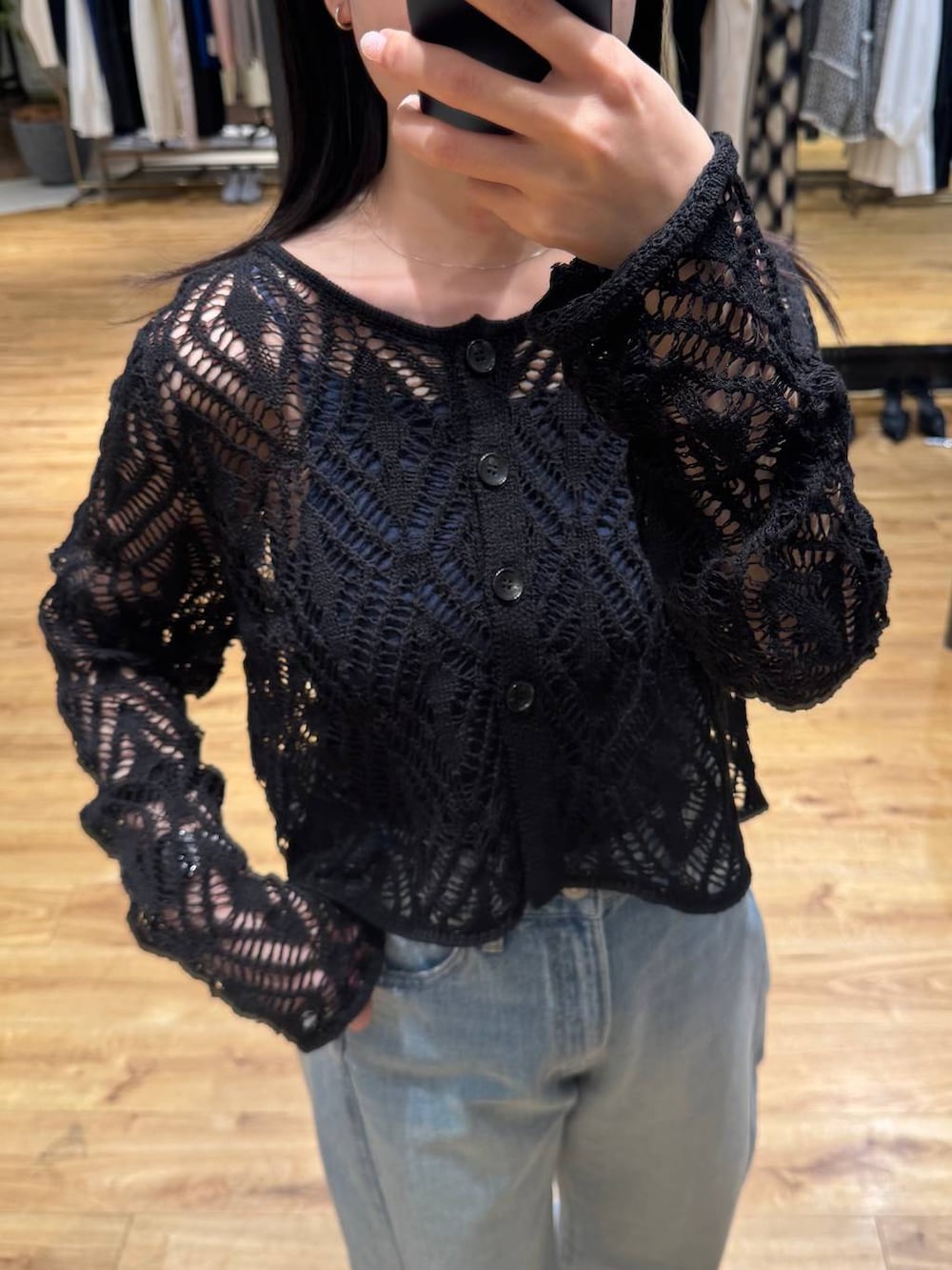 ブルー系のデニムパンツ、ブラック系のカーディガン/ボレロ、ホワイト系のサンダルを着用したレディースの春コーディネートの4枚目の写真