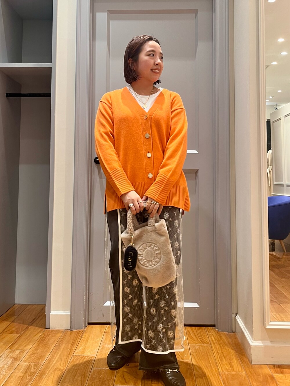 オレンジ系のカーディガン/ボレロ、ホワイト系のTシャツ/カットソー、ホワイト系のスカートを着用したレディースの冬コーディネートの2枚目の写真