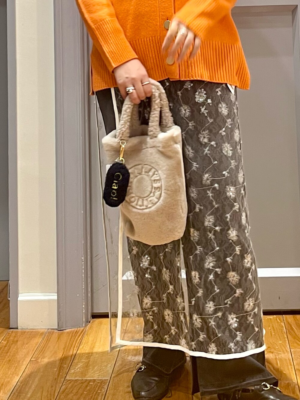 オレンジ系のカーディガン/ボレロ、ホワイト系のTシャツ/カットソー、ホワイト系のスカートを着用したレディースの冬コーディネートの3枚目の写真