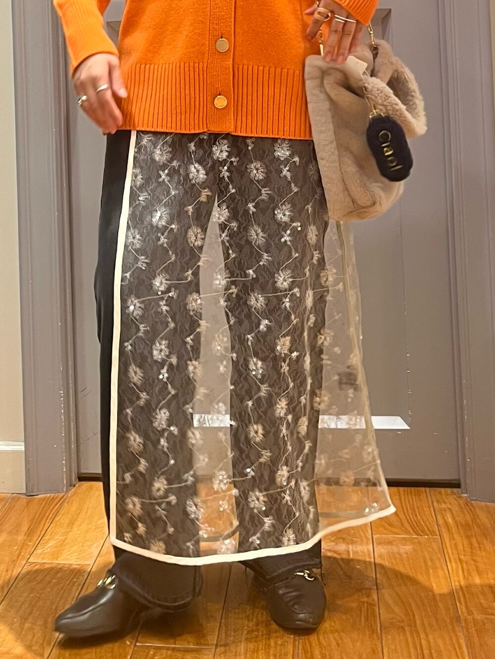 オレンジ系のカーディガン/ボレロ、ホワイト系のTシャツ/カットソー、ホワイト系のスカートを着用したレディースの冬コーディネートの6枚目の写真