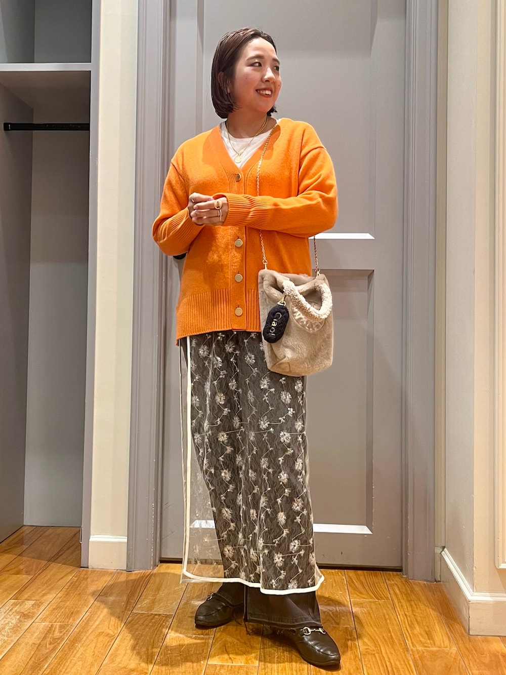 オレンジ系のカーディガン/ボレロ、ホワイト系のTシャツ/カットソー、ホワイト系のスカートを着用したレディースの冬コーディネートの4枚目の写真