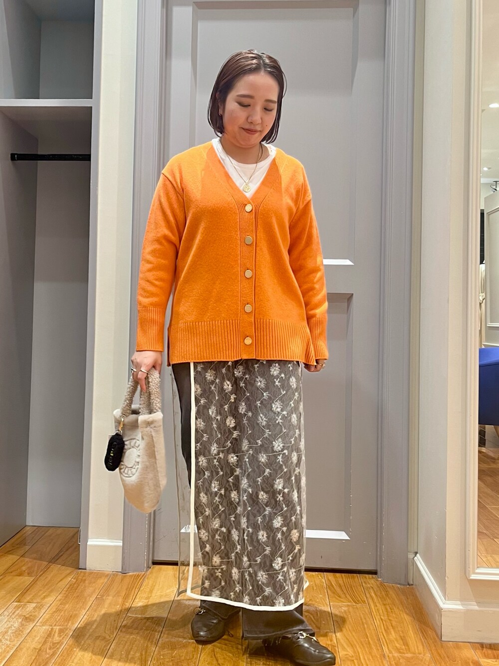 オレンジ系のカーディガン/ボレロ、ホワイト系のTシャツ/カットソー、ホワイト系のスカートを着用したレディースの冬コーディネートの8枚目の写真