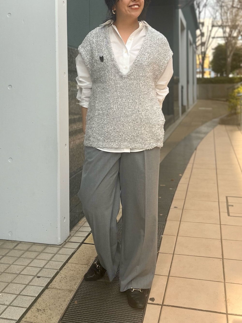 グレー系のベスト、ホワイト系のシャツ/ブラウス、グレー系のその他パンツを着用したレディースの冬コーディネートの2枚目の写真