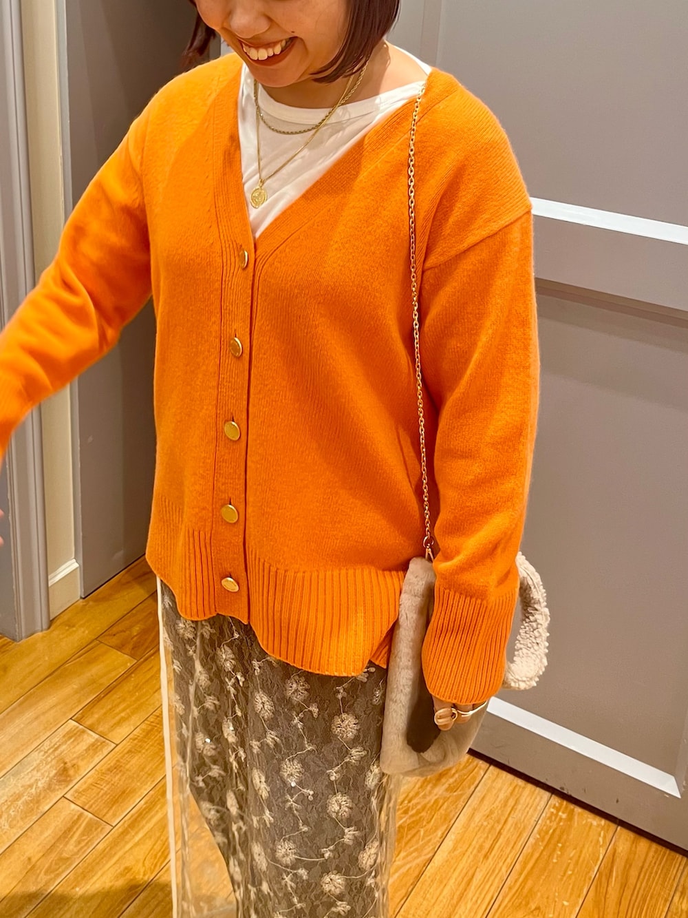 オレンジ系のカーディガン/ボレロ、ホワイト系のTシャツ/カットソー、ホワイト系のスカートを着用したレディースの冬コーディネートの7枚目の写真
