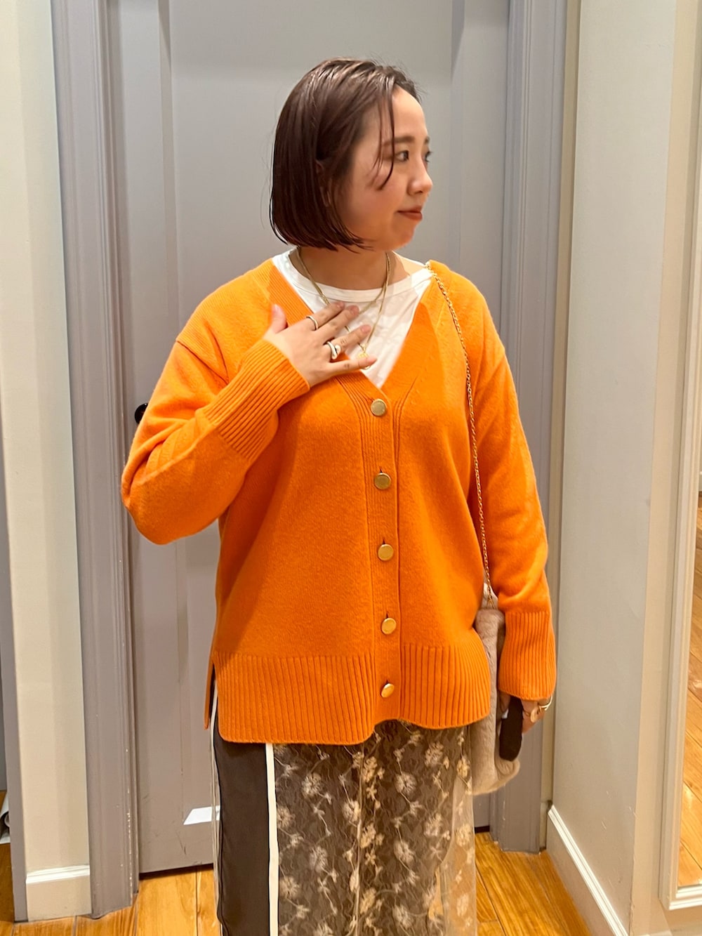 オレンジ系のカーディガン/ボレロ、ホワイト系のTシャツ/カットソー、ホワイト系のスカートを着用したレディースの冬コーディネートの5枚目の写真