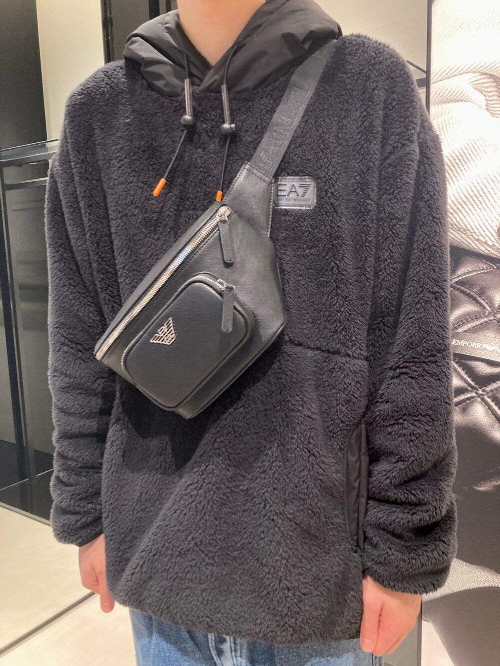 ブラック系のスウェット、ブルー系のデニムパンツ、ブラック系のボディバッグ/ウエストポーチを着用したメンズの冬コーディネートの2枚目の写真