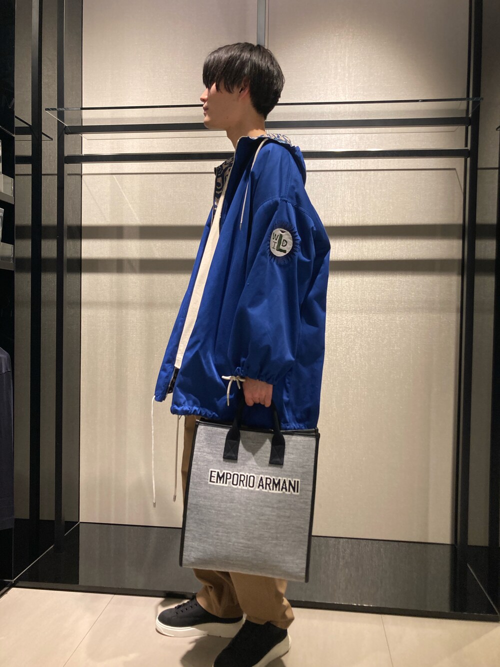 ブルー系のマウンテンパーカー、グレー系のトートバッグ、ベージュ系のパンツを着用したメンズの冬コーディネートの2枚目の写真