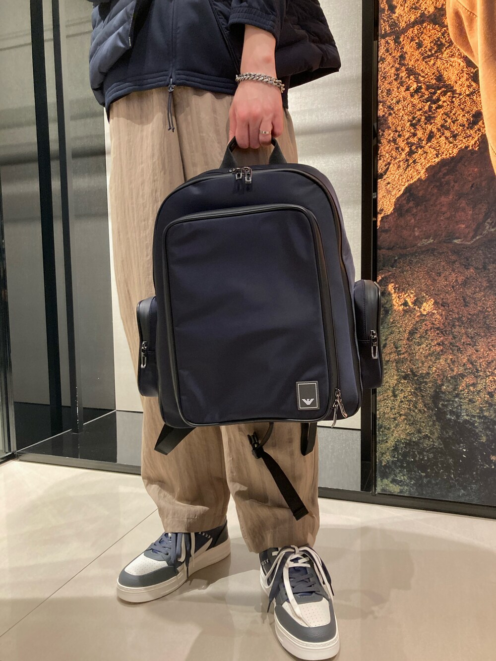 ブルー系のダウンベスト、ブルー系のスウェット、ベージュ系のスラックスを着用したメンズの春コーディネートの2枚目の写真