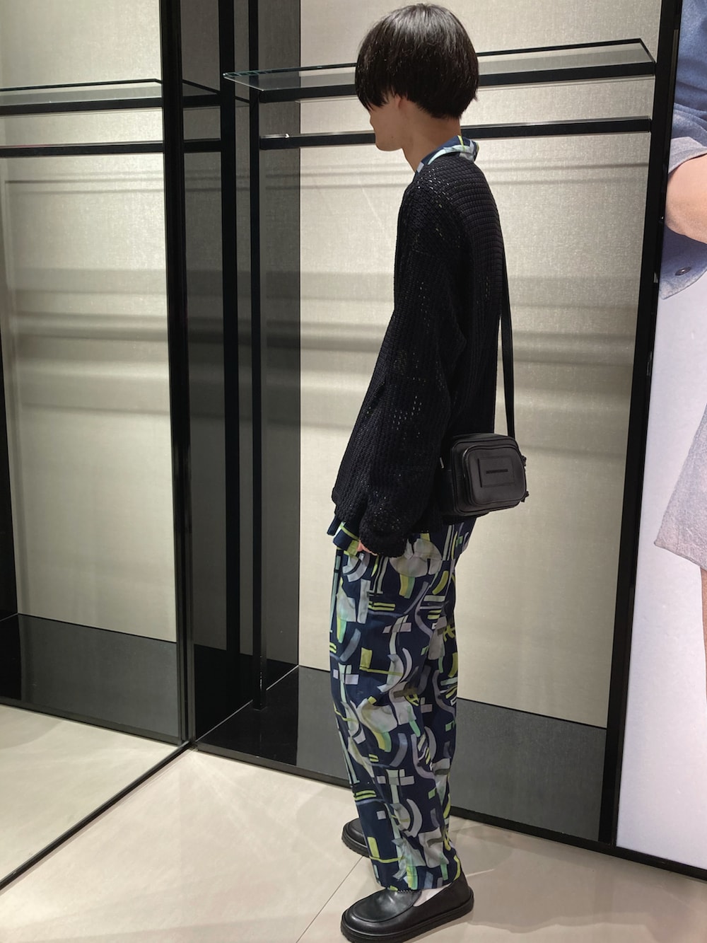 ブラック系のニット/セーター、イエロー系のシャツ/ブラウス、イエロー系のスラックスを着用したメンズの春コーディネートの2枚目の写真