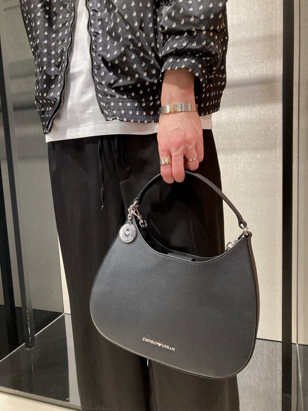 ブラック系のブルゾン、ホワイト系のTシャツ/カットソー、ブラック系のスラックスを着用したメンズの春コーディネートの2枚目の写真