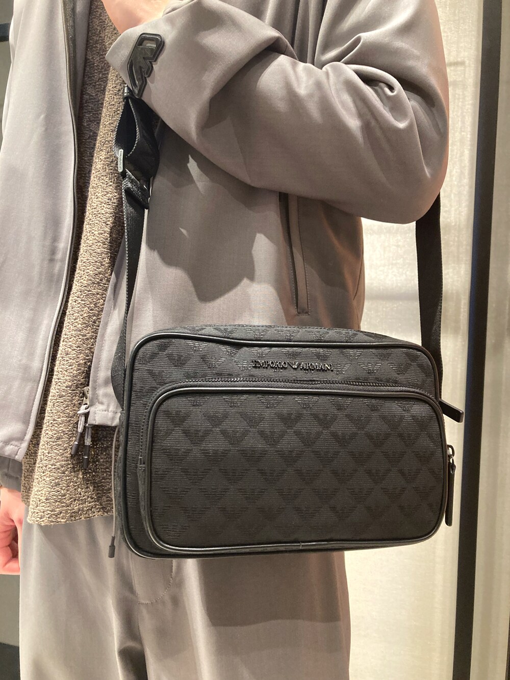 ベージュ系のトップス、グリーン系のマウンテンパーカー、グレー系のスラックスを着用したメンズの春コーディネートの2枚目の写真