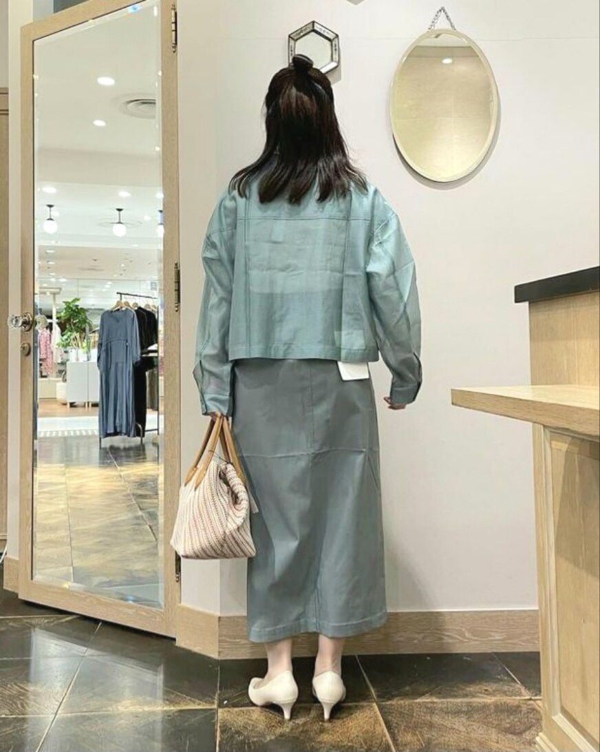 グリーン系のトップス、グリーン系のスカート、イエロー系のハンドバッグを着用したレディースの春コーディネートの5枚目の写真