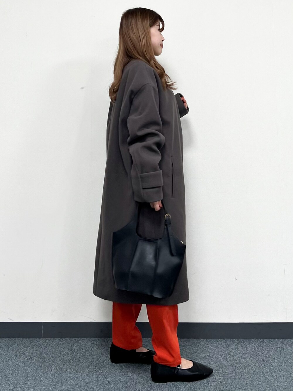 ブラウン系のノーカラーコート、ベージュ系のTシャツ/カットソー、ブラック系のトートバッグを着用したレディースの冬コーディネートの2枚目の写真