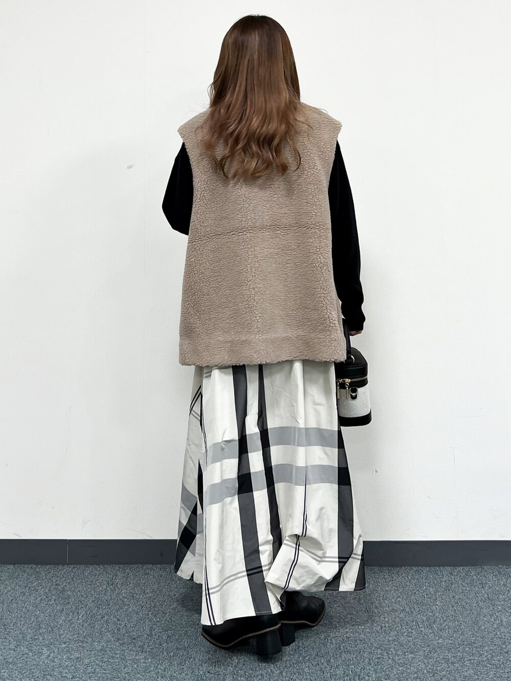 ブラック系のニット/セーター、ベージュ系のベスト、ホワイト系のスカートを着用したレディースの冬コーディネートの3枚目の写真