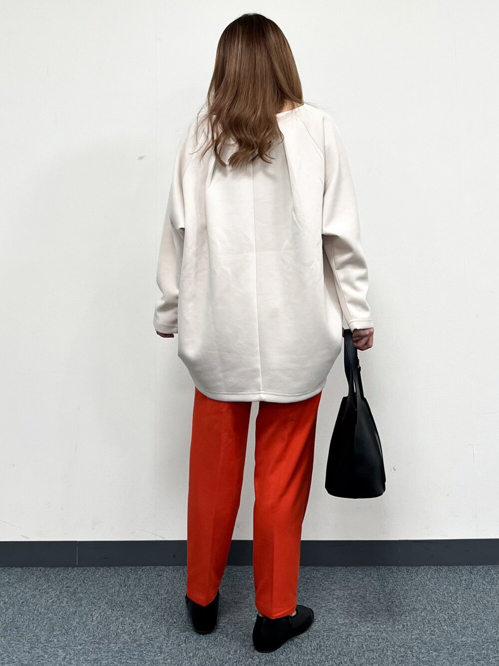 ブラウン系のノーカラーコート、ベージュ系のTシャツ/カットソー、ブラック系のトートバッグを着用したレディースの冬コーディネートの5枚目の写真