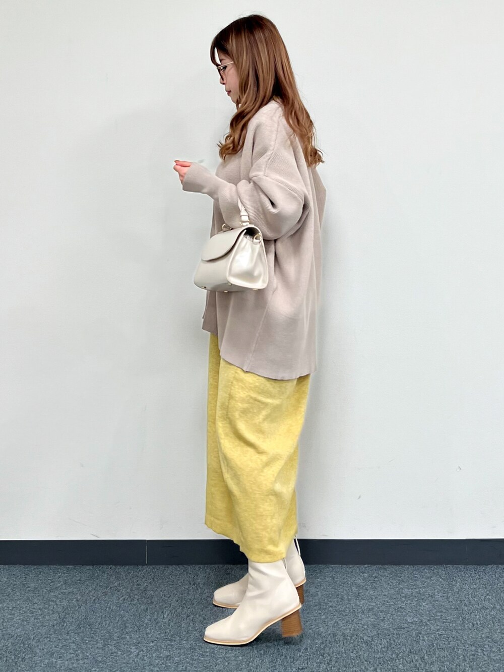 ベージュ系のカーディガン/ボレロ、ベージュ系のハンドバッグ、イエロー系のワンピースを着用したレディースの冬コーディネートの4枚目の写真