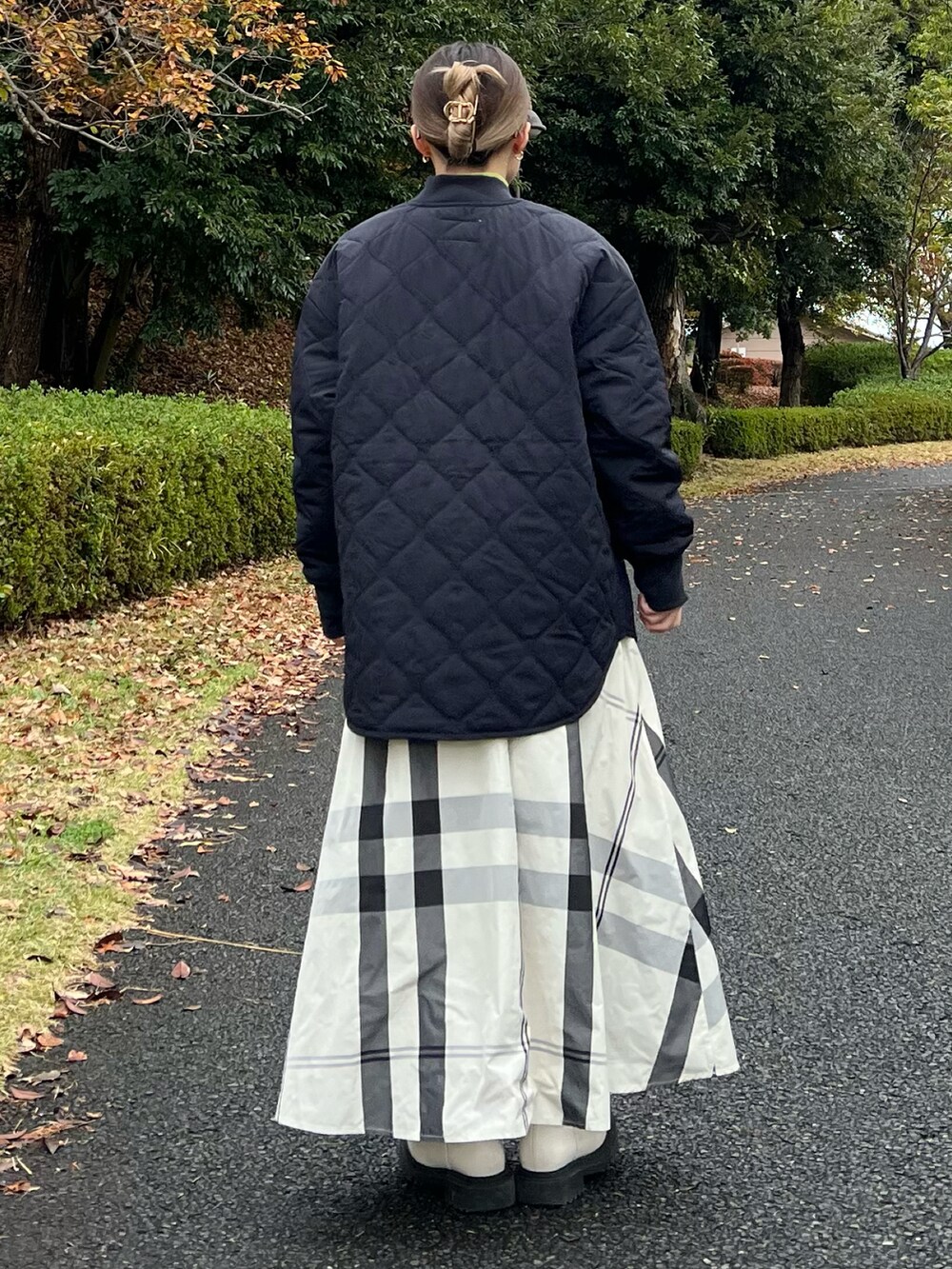 ブラック系のブルゾン、グリーン系のニット/セーター、ホワイト系のスカートを着用したレディースの冬コーディネートの3枚目の写真