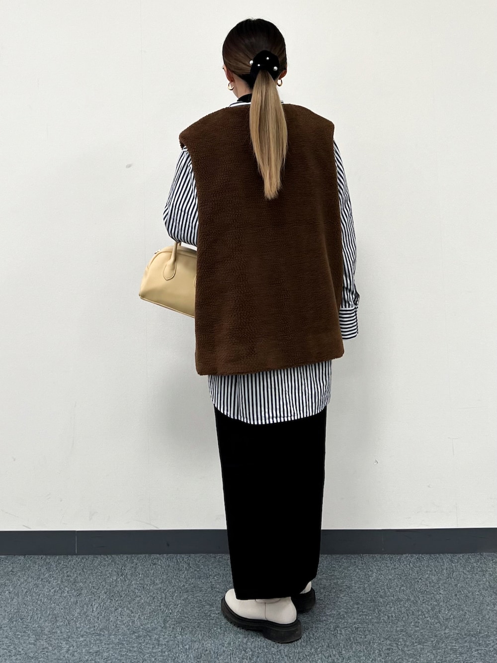 ブラウン系のベスト、ブルー系のシャツ/ブラウス、イエロー系のハンドバッグを着用したレディースの冬コーディネートの3枚目の写真