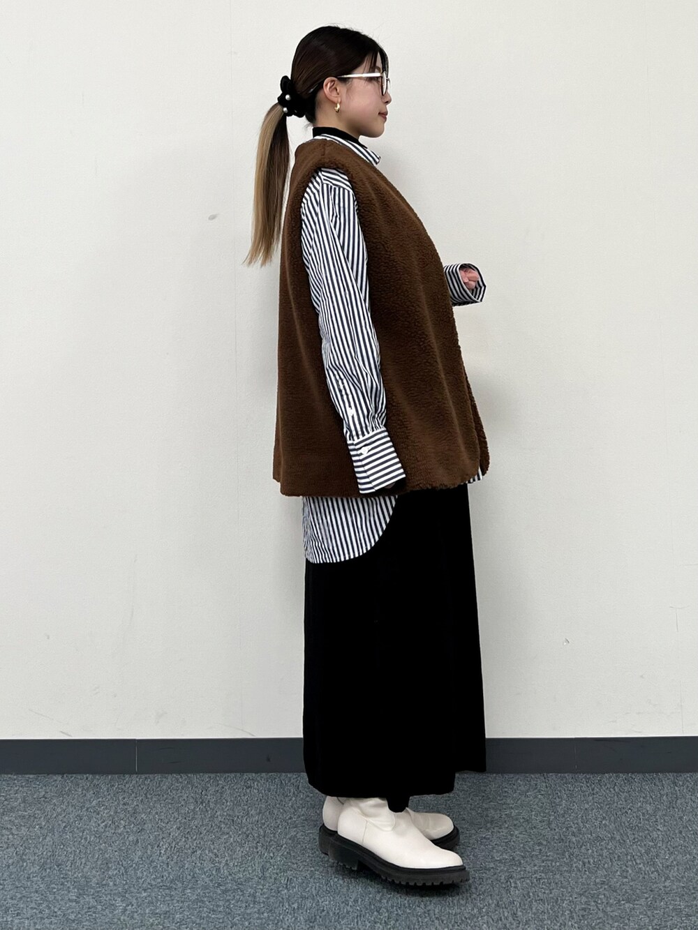 ブラウン系のベスト、ブルー系のシャツ/ブラウス、イエロー系のハンドバッグを着用したレディースの冬コーディネートの2枚目の写真