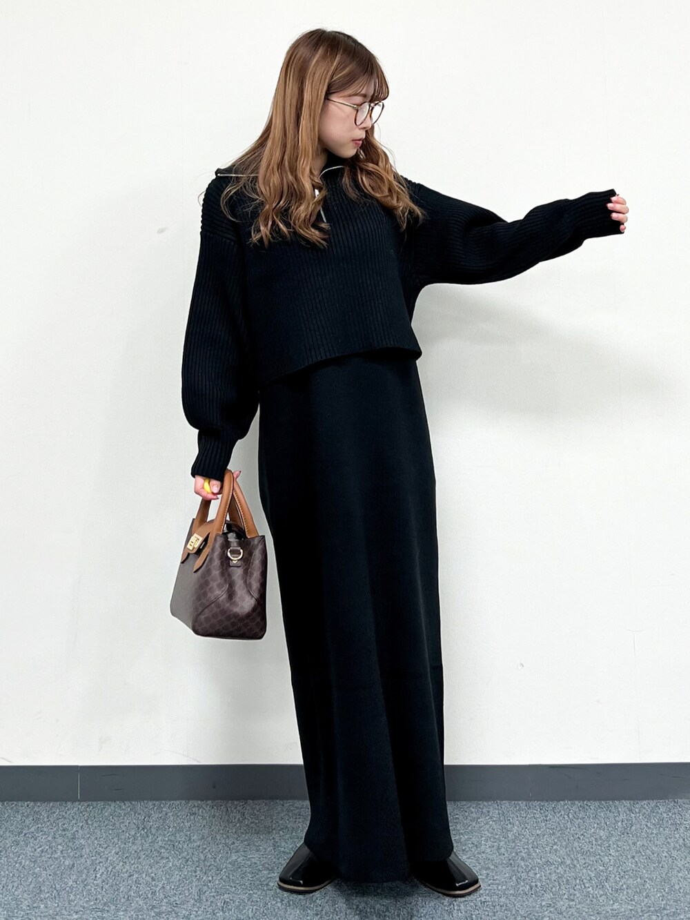 ブラック系のワンピース、ブラウン系のショルダーバッグ、ブラック系のブーツを着用したレディースの冬コーディネートの5枚目の写真