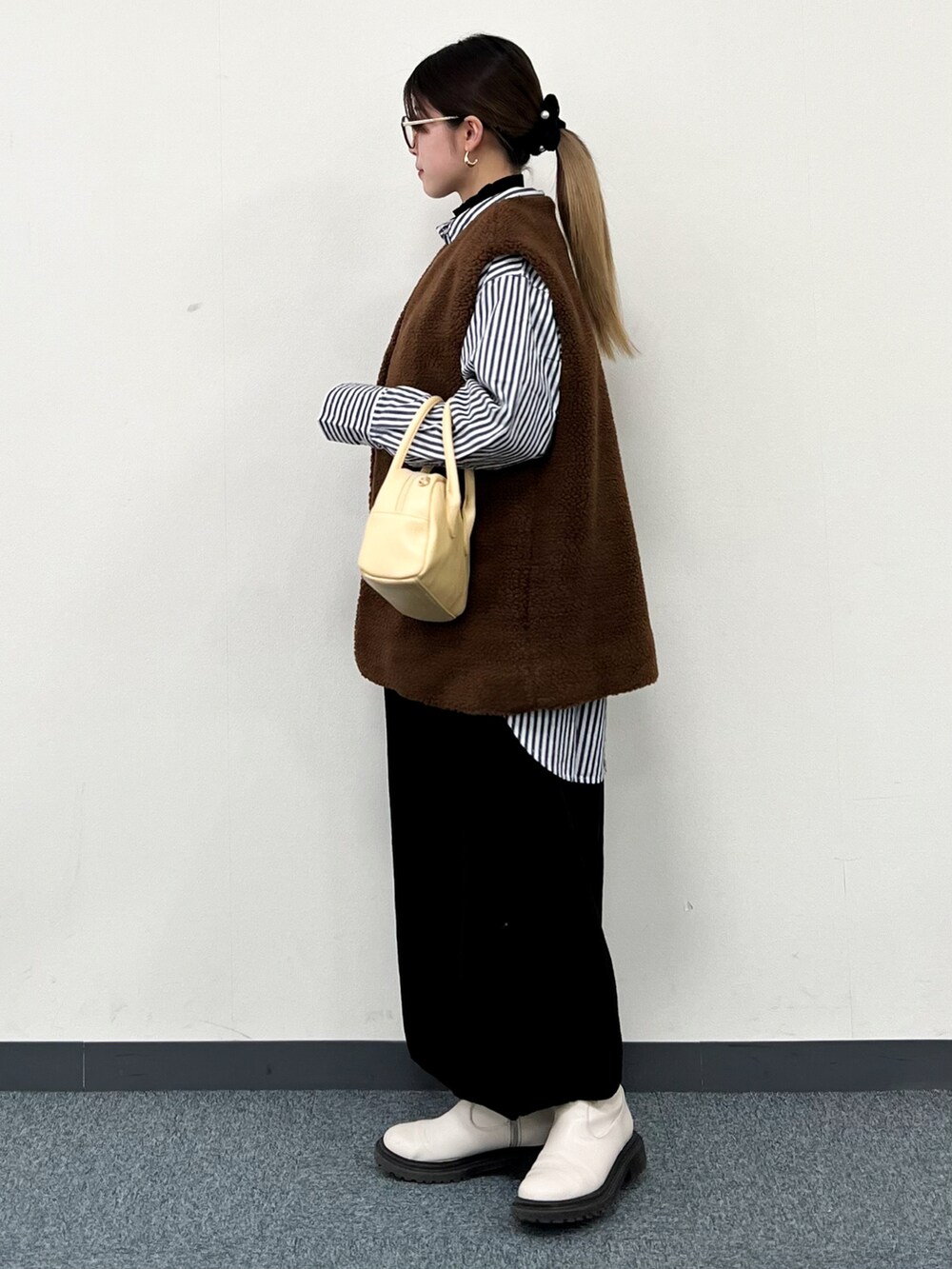 ブラウン系のベスト、ブルー系のシャツ/ブラウス、イエロー系のハンドバッグを着用したレディースの冬コーディネートの4枚目の写真