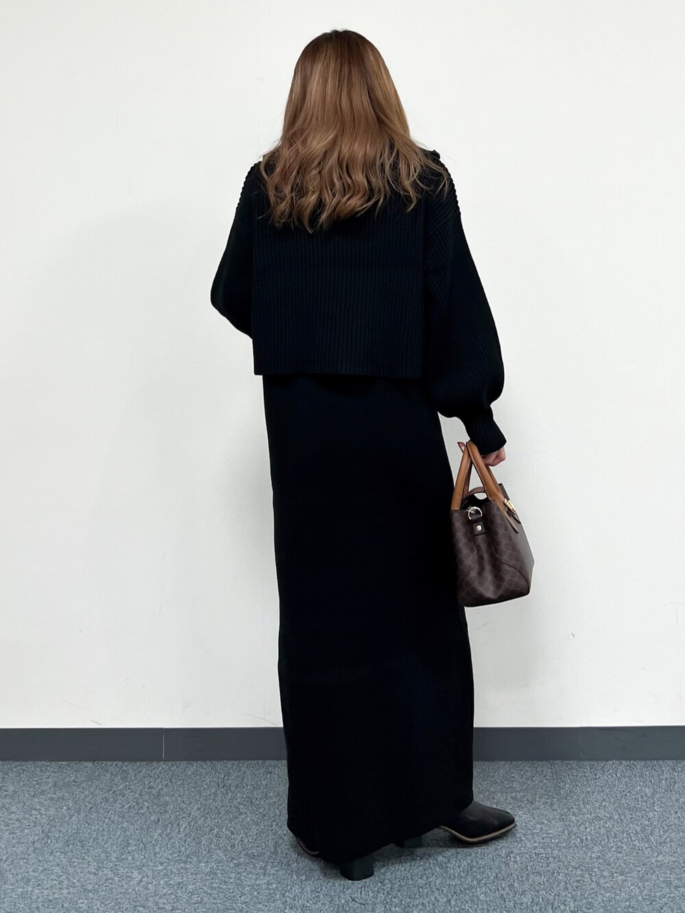 ブラック系のワンピース、ブラウン系のショルダーバッグ、ブラック系のブーツを着用したレディースの冬コーディネートの3枚目の写真