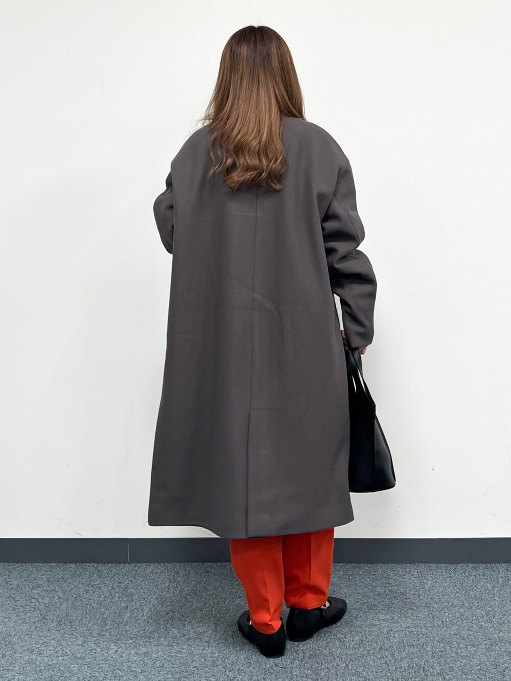 ブラウン系のノーカラーコート、ベージュ系のTシャツ/カットソー、ブラック系のトートバッグを着用したレディースの冬コーディネートの3枚目の写真