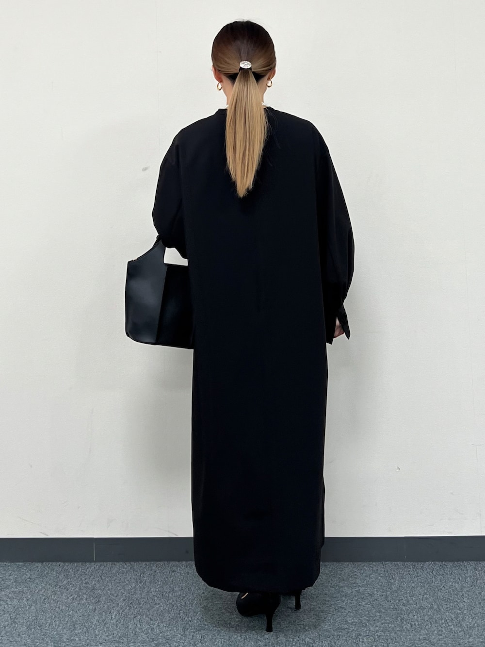 ブラック系のトートバッグ、ブラック系のワンピース、ブラック系のパンプスを着用したレディースの冬コーディネートの3枚目の写真