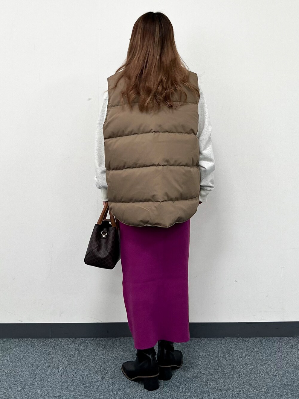 ベージュ系のダウンベスト、ホワイト系のスウェット、ブラウン系のショルダーバッグを着用したレディースの冬コーディネートの3枚目の写真