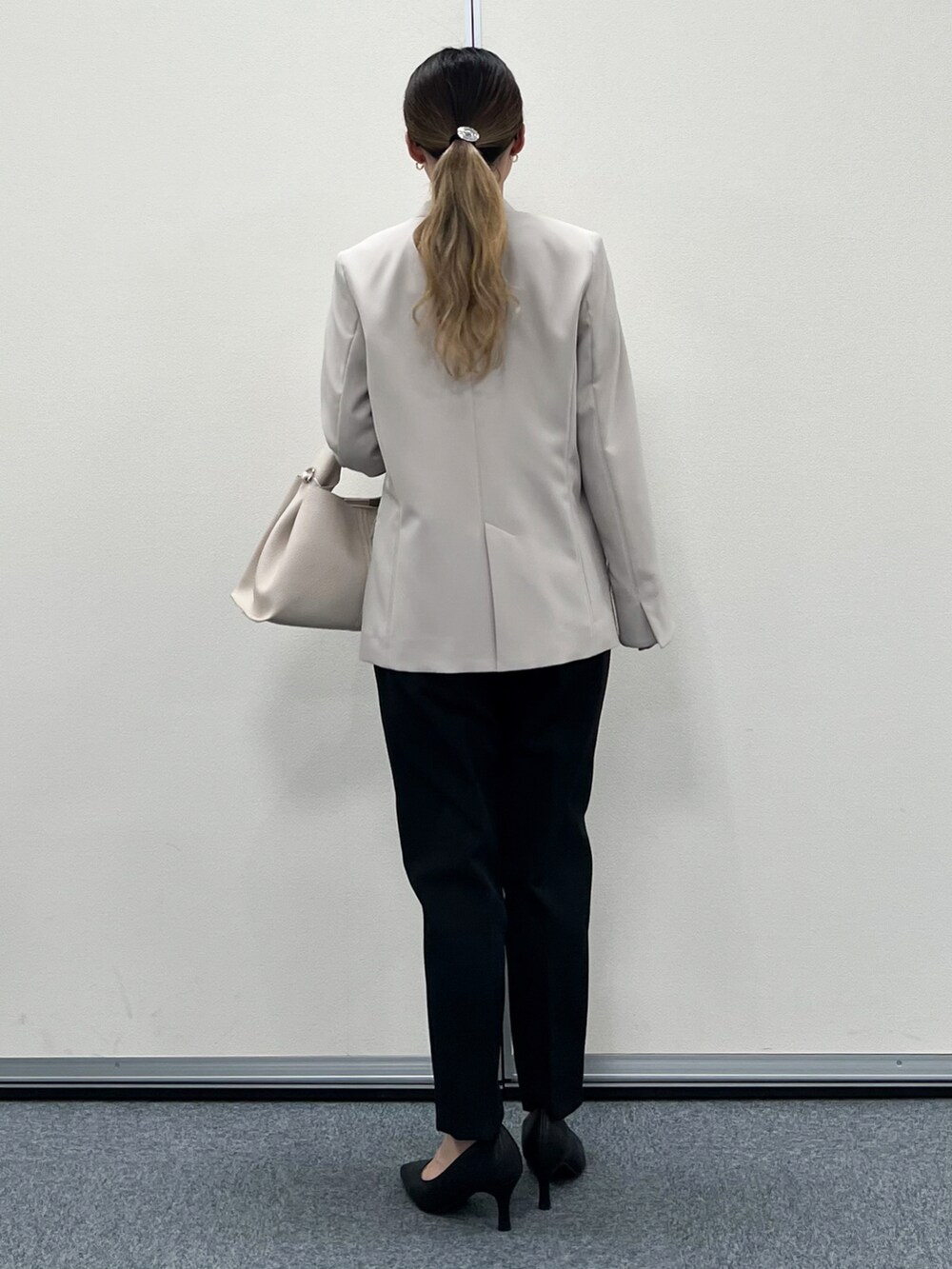 グレー系のノーカラージャケット、ベージュ系のトートバッグ、ブラック系のその他パンツを着用したレディースの冬コーディネートの3枚目の写真