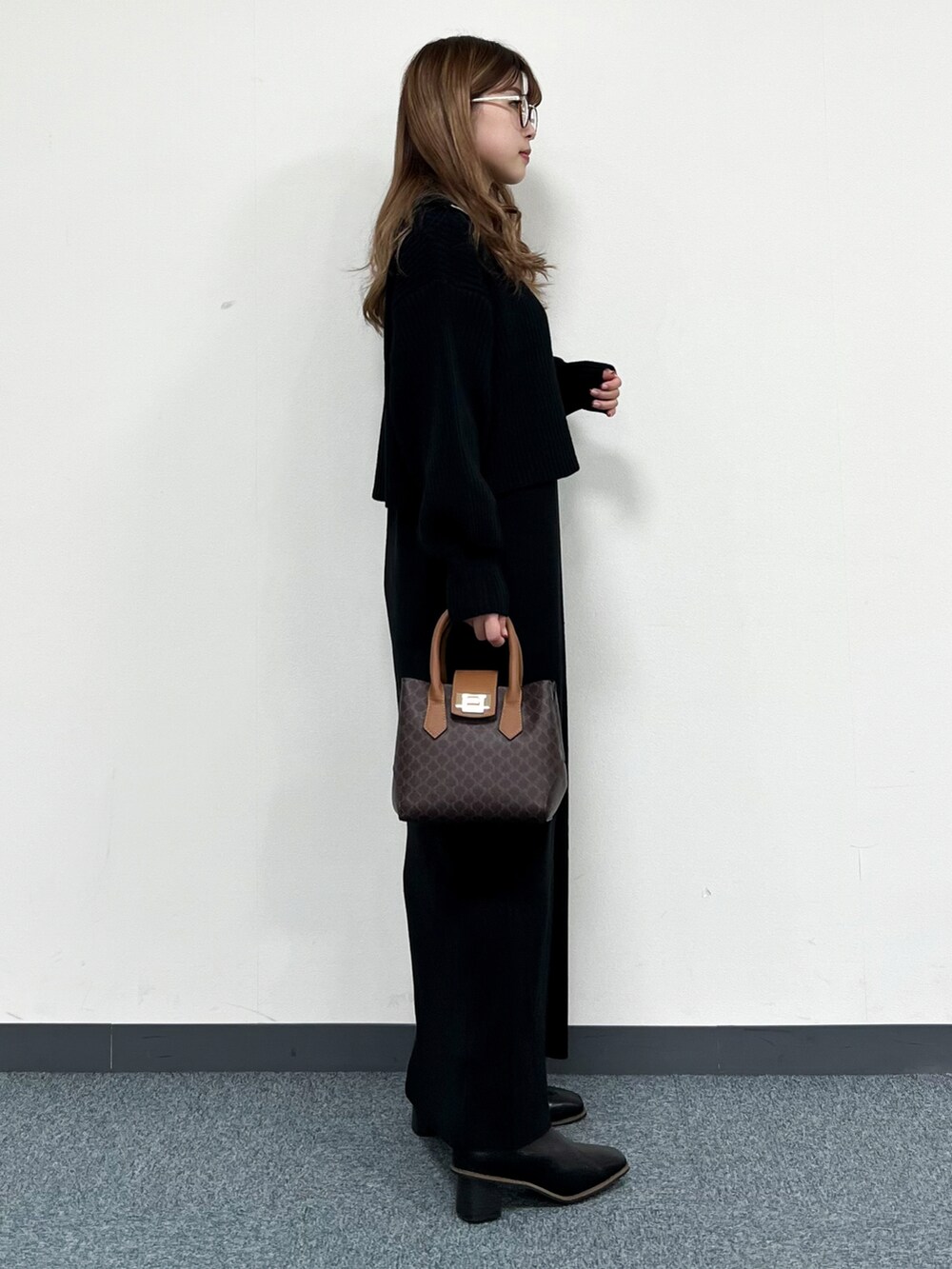 ブラック系のワンピース、ブラウン系のショルダーバッグ、ブラック系のブーツを着用したレディースの冬コーディネートの2枚目の写真