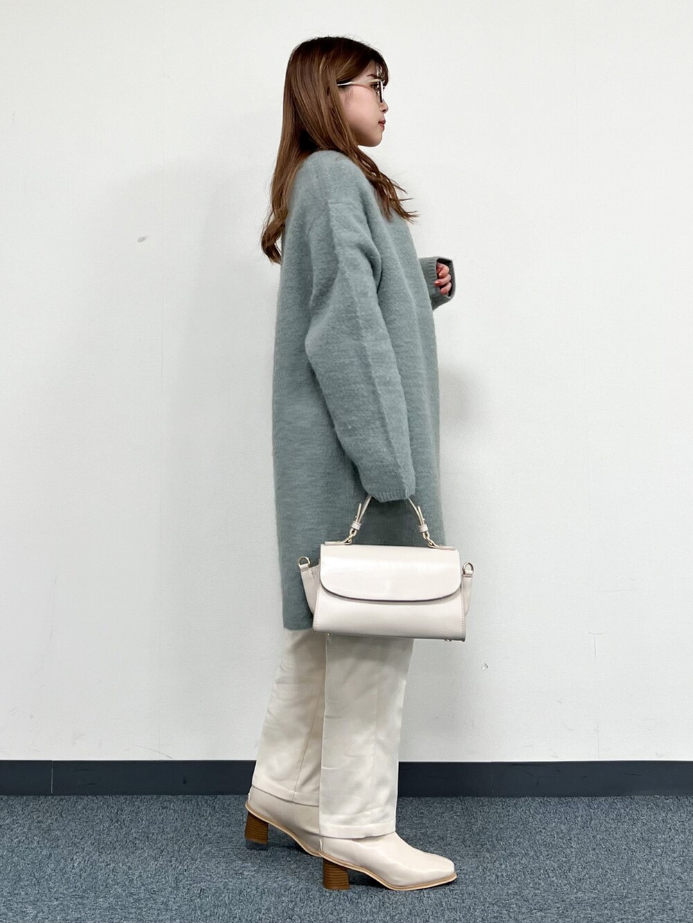 グリーン系のカーディガン/ボレロ、ベージュ系のハンドバッグ、ホワイト系のその他パンツを着用したレディースの冬コーディネートの2枚目の写真