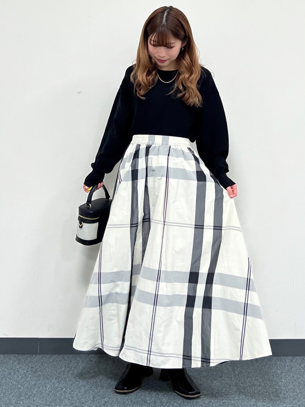 ブラック系のニット/セーター、ベージュ系のベスト、ホワイト系のスカートを着用したレディースの冬コーディネートの5枚目の写真