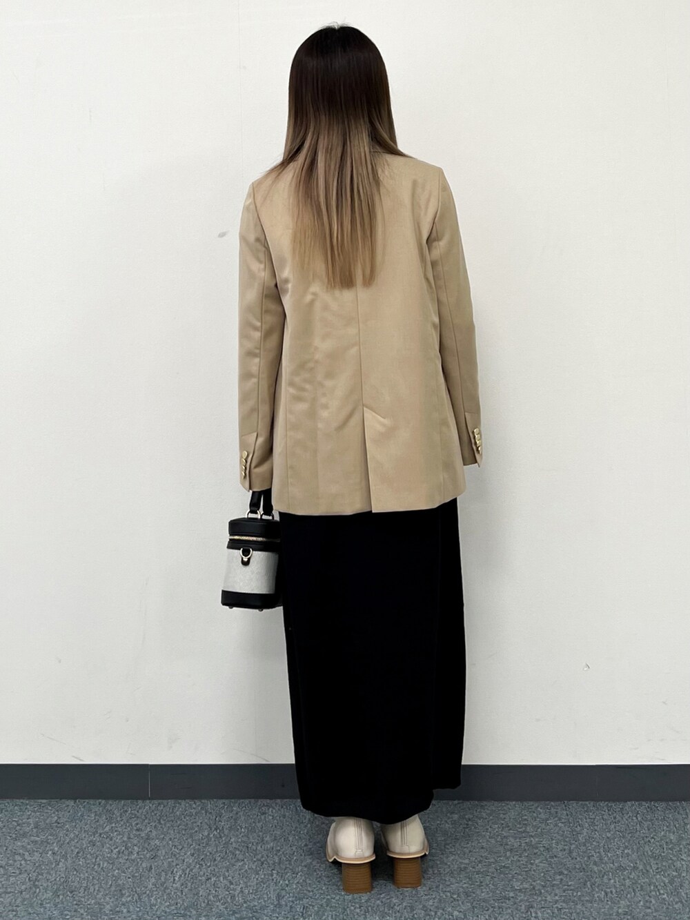 ブラック系のワンピース、ベージュ系のテーラードジャケット、ブラック系のショルダーバッグを着用したレディースの冬コーディネートの3枚目の写真