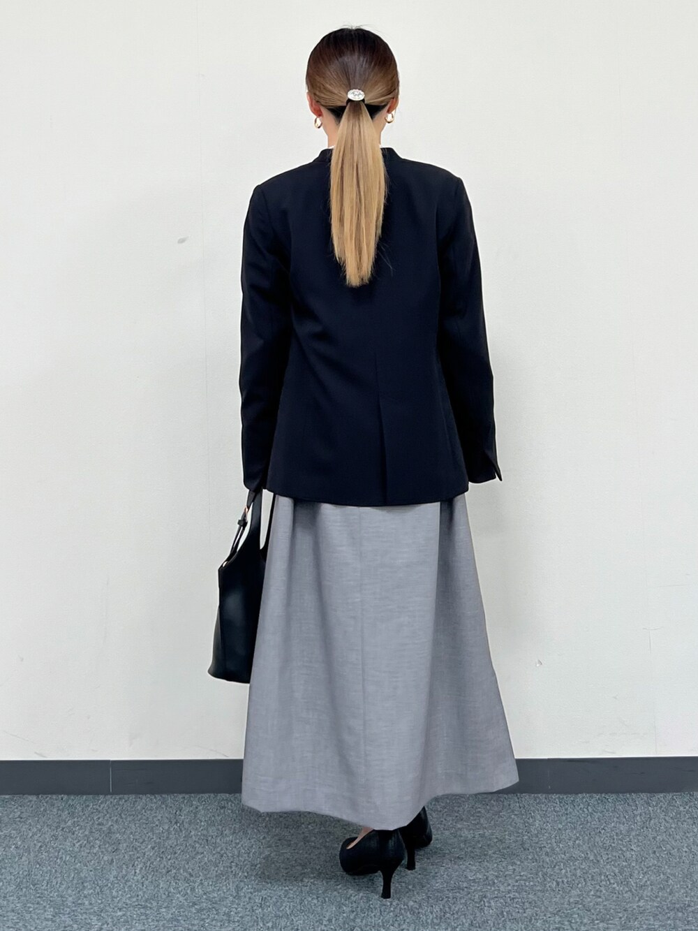 ブラック系のノーカラージャケット、グレー系のワンピース、ブラック系のトートバッグを着用したレディースの冬コーディネートの3枚目の写真