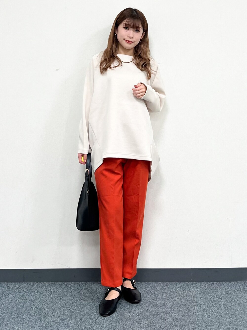 ブラウン系のノーカラーコート、ベージュ系のTシャツ/カットソー、ブラック系のトートバッグを着用したレディースの冬コーディネートの4枚目の写真