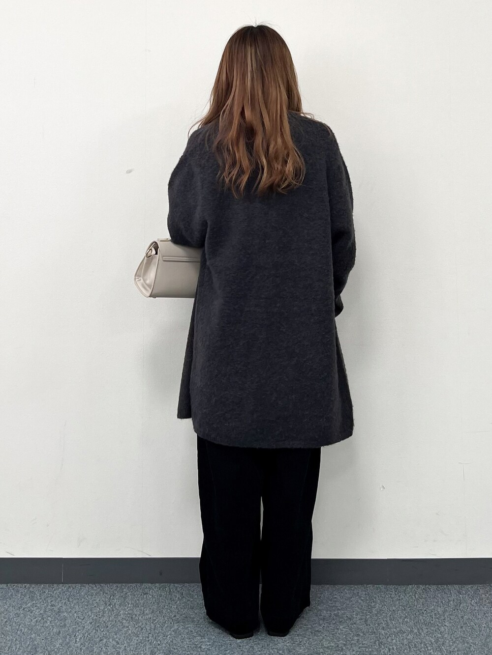 グレー系のカーディガン/ボレロ、ホワイト系のニット/セーター、ベージュ系のハンドバッグを着用したレディースの冬コーディネートの4枚目の写真