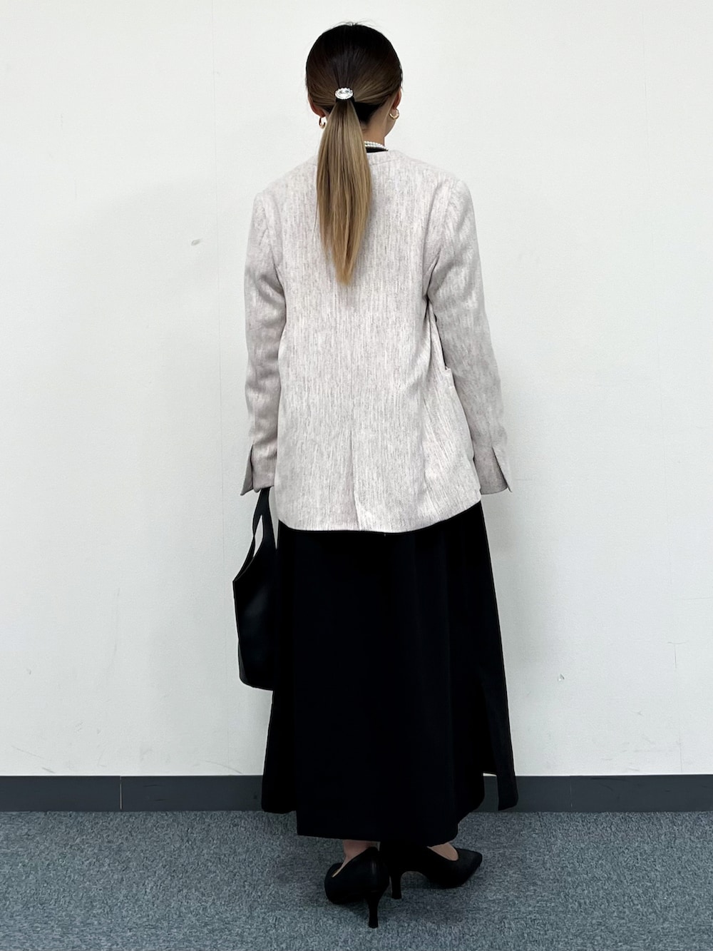 ベージュ系のノーカラージャケット、ブラック系のワンピース、ブラック系のトートバッグを着用したレディースの冬コーディネートの3枚目の写真