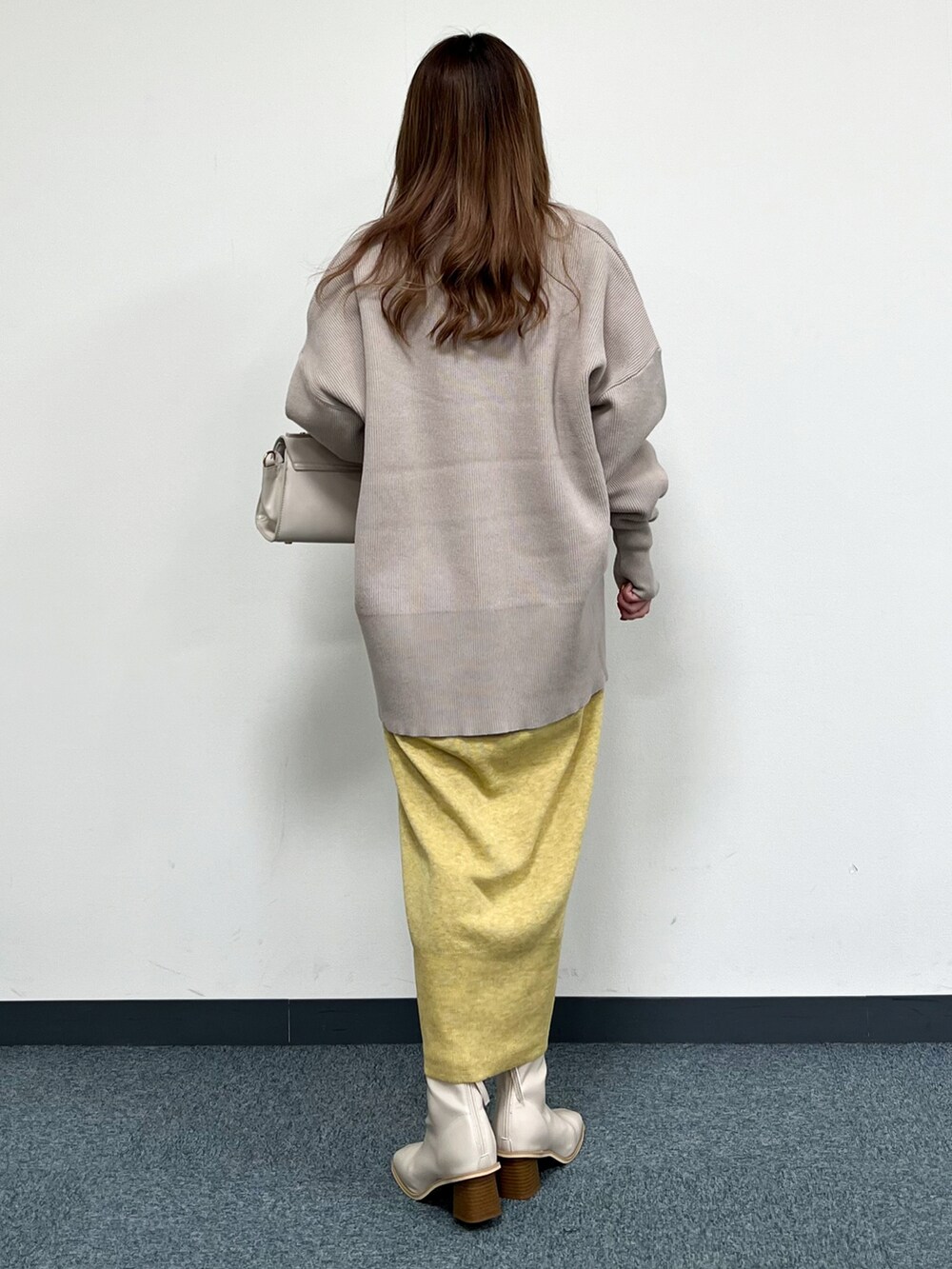 ベージュ系のカーディガン/ボレロ、ベージュ系のハンドバッグ、イエロー系のワンピースを着用したレディースの冬コーディネートの3枚目の写真
