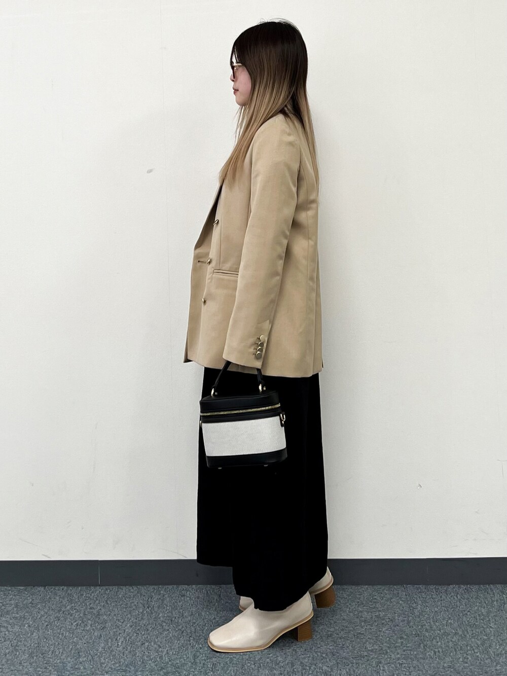 ブラック系のワンピース、ベージュ系のテーラードジャケット、ブラック系のショルダーバッグを着用したレディースの冬コーディネートの4枚目の写真