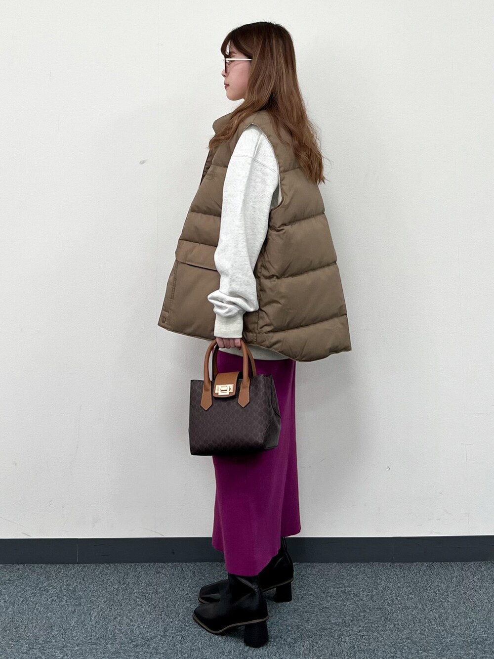 ベージュ系のダウンベスト、ホワイト系のスウェット、ブラウン系のショルダーバッグを着用したレディースの冬コーディネートの4枚目の写真