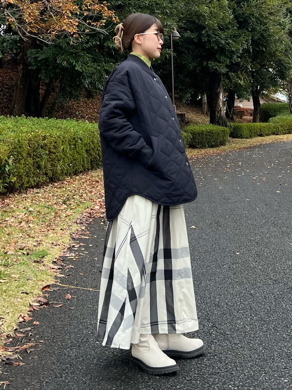 ブラック系のブルゾン、グリーン系のニット/セーター、ホワイト系のスカートを着用したレディースの冬コーディネートの2枚目の写真