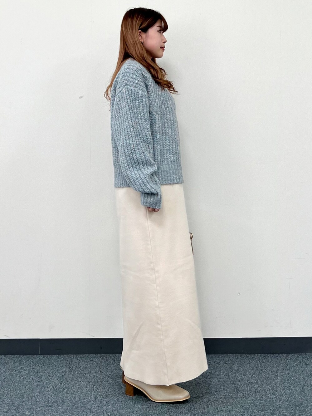 ブルー系のニット/セーター、ベージュ系のハンドバッグ、ベージュ系のワンピースを着用したレディースの冬コーディネートの2枚目の写真