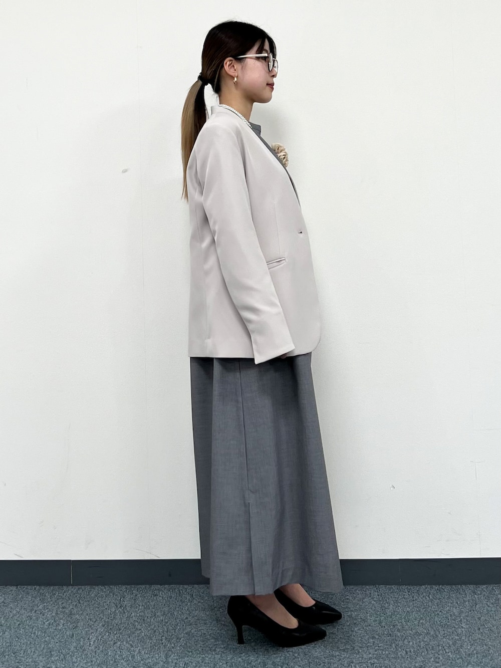 グレー系のノーカラージャケット、グレー系のワンピース、ブラック系のパンプスを着用したレディースの冬コーディネートの2枚目の写真