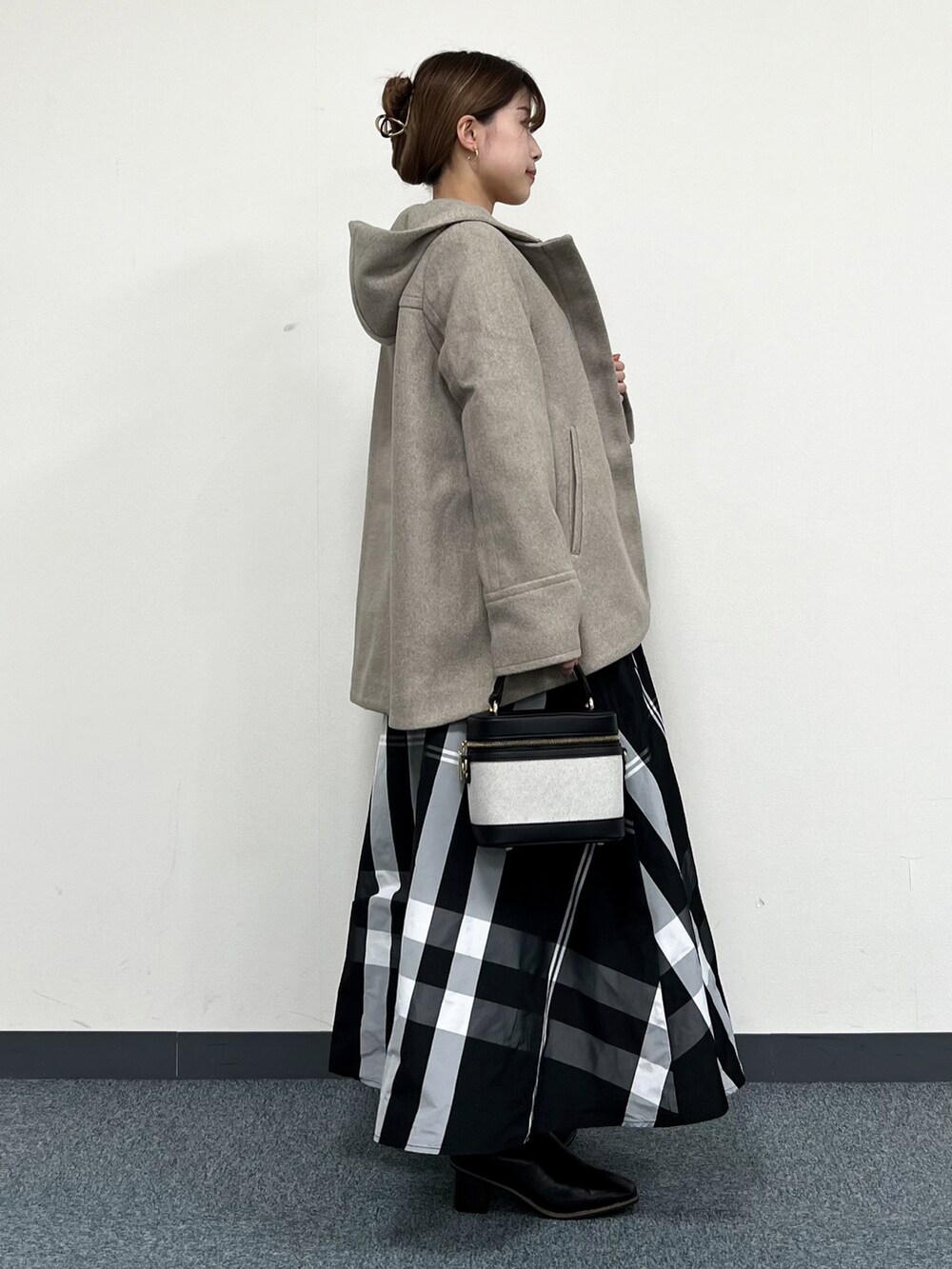 ブラウン系のその他アウター、イエロー系のニット/セーター、ブラック系のスカートを着用したレディースの冬コーディネートの2枚目の写真