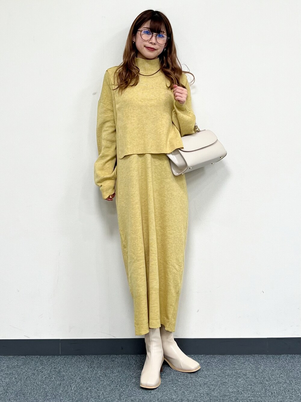 ベージュ系のカーディガン/ボレロ、ベージュ系のハンドバッグ、イエロー系のワンピースを着用したレディースの冬コーディネートの5枚目の写真